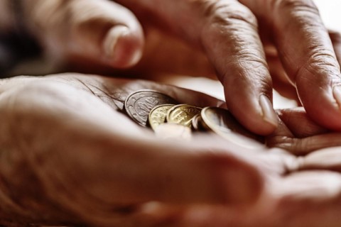 Coin money in the wrinkled hand of a senior citizen, symbolising poverty and poverty in old age,