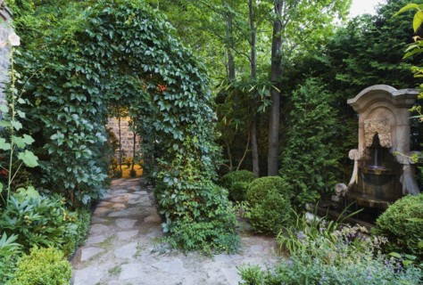 Grey flagstone path through arbour covered with climbing Vitis, Vines, Renaissance style water