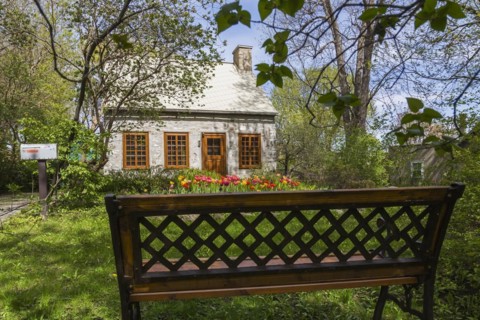 Old circa 1750 Canadiana style fieldstone house facade with brown stained wooden windows, door and