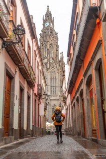 A tourist woman walking along a beautiful street next to the Church of San Juan Bautista, Arucas
