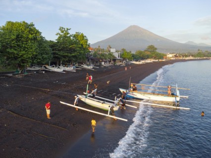Fishermen loading fish from their outrigger boats in the morning on the black beach of Amed, Mount