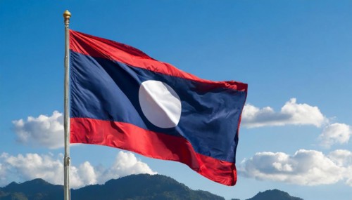 The flag of Laos flutters in the wind, isolated against a blue sky