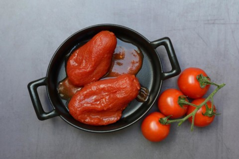 Whole tinned tomatoes in a pot and tomatoes