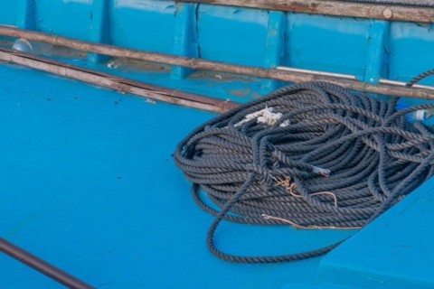 Black rope coiled up in bottom of blue fishing boat in South Korea