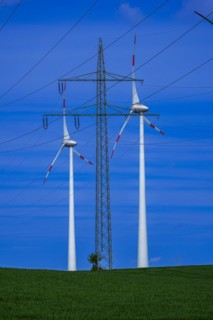 Power pylon with high-voltage lines and wind turbines at the Avacon substation Helmstedt,