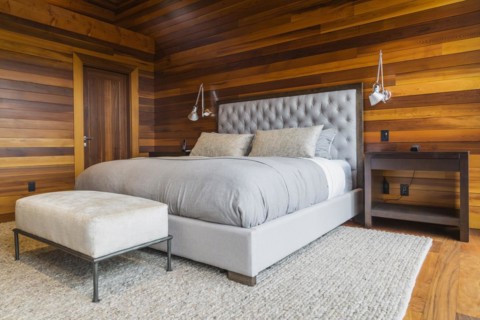 King size bed with grey upholstered panel headboard, ottoman and wooden end tables in master