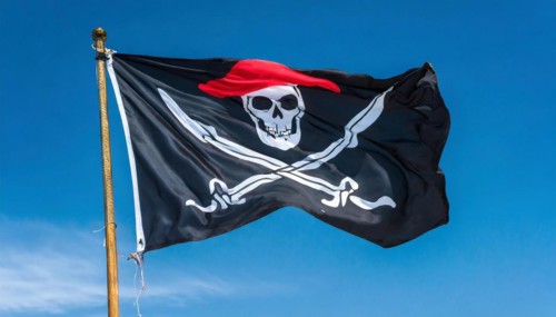 The pirate flag flutters in the wind, isolated against the blue sky