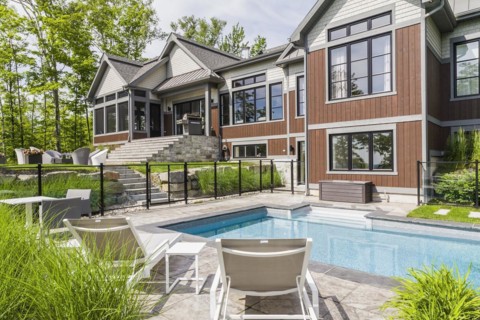 In-ground swimming pool and rear view of contemporary natural stone and brown stained wood and