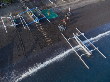 Fishermen unload their catch from their outrigger boat in the morning. Amed, Karangasem, Bali,