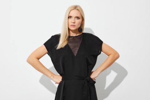 Dissatisfied woman stands with her fists on her sides on white background