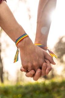 Vertical close-up of a gay men with rainbow bracelets holding hands