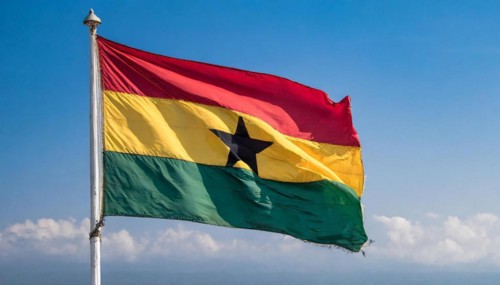 The flag of Ghana flutters in the wind, isolated against a blue sky