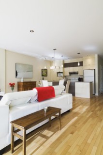 White leather sofa in living room and view of dining room area and kitchen inside a renovated