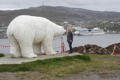 Polar bear sculpture in front of the town of Hammerfest with cruise ship Aida in the harbour,