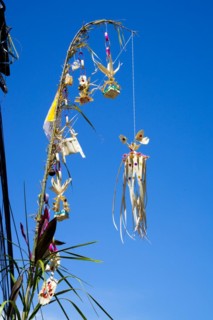 Ornate jewellery woven from palm leaves on bamboo poles, on a village street in Amed, Karangasem,