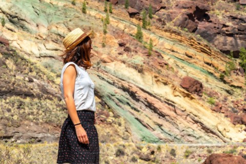 A tourist woman at the Natural Monument Azulejos de Veneguera or Rainbow Rocks in Mogan, Gran