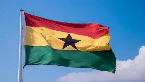 The flag of Ghana flutters in the wind, isolated against a blue sky