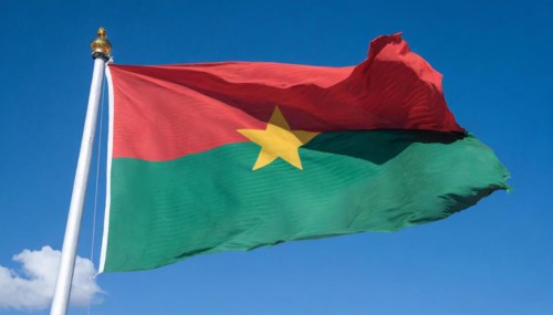 The flag of Burkina Faso flutters in the wind, isolated against the blue sky