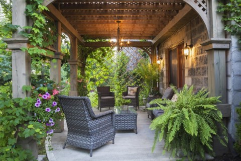 Rear of Renaissance grey stone and mortar castle style home with concrete patio and lattice covered
