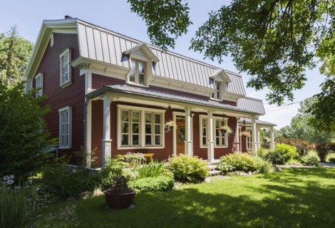 Old 1892 burgundy with white trim pinewood plank house facade with mansarde style grey sheet metal