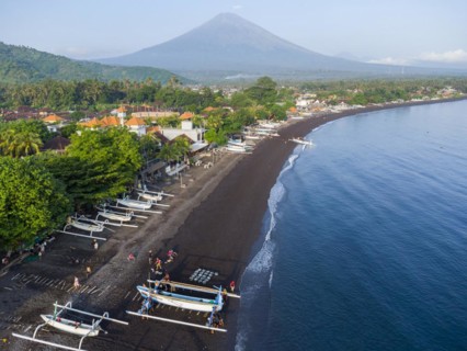 Fishermen unload their catch from their outrigger boat in the morning, in the background Gunung