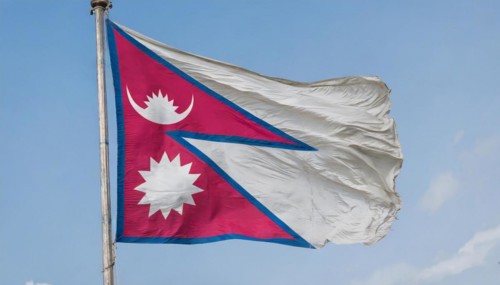 The flag of Nepal, fluttering in the wind, isolated against a blue sky