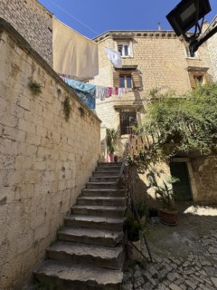 Stone staircase in a sunny alleyway of the old town centre with hanging laundry, Trogir, Dalmatia,