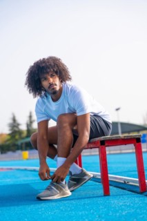 Vertical portrait of a concentrated young african american running getting ready to train tying her