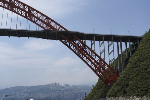 Chongqing, Chongqing Province, A high red bridge spans a river, with a city in the sunny