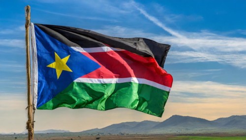 The flag of South Sudan, fluttering in the wind, isolated, against the blue sky