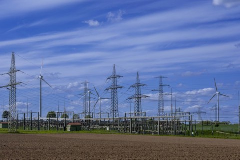 Power pylons with high-voltage lines and wind turbines at the Avacon substation in Helmstedt,