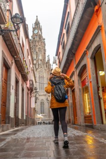 A tourist woman walking along a beautiful street next to the Church of San Juan Bautista, Arucas