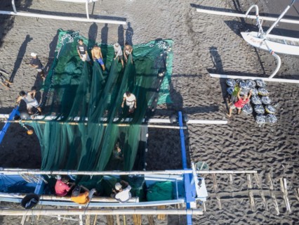 Fishermen unload their catch from their outrigger boat in the morning. Amed, Karangasem, Bali,