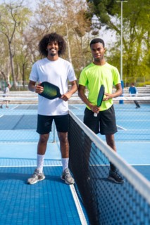 Vertical Portrait of two young african american pickleball players standing looking at camera