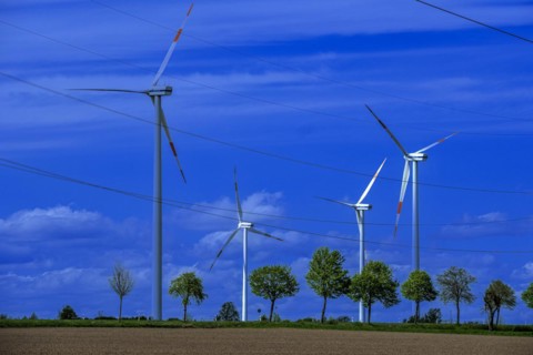 Wind turbines and high-voltage power lines on the K63 road with trees at the Avacon substation