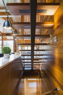 Underside view of illuminated wooden staircase with opened steps and clear glass railing inside