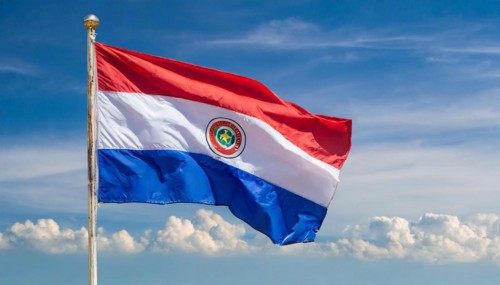The flag of Paraguay flutters in the wind, isolated against a blue sky