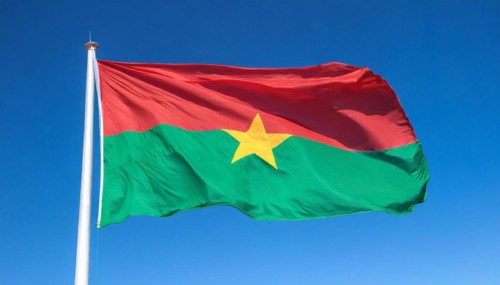 The flag of Burkina Faso flutters in the wind, isolated against the blue sky