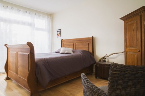 Antique wooden queen size sleigh bed in master bedroom inside a renovated ground floor apartment in
