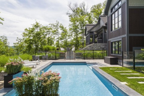 In-ground swimming pool and rear view of contemporary natural stone and brown stained wood and