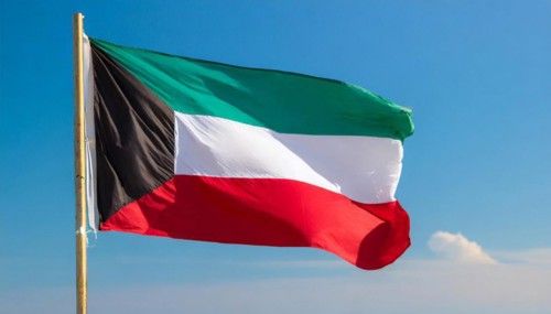 The flag of Kuwait flutters in the wind, isolated against a blue sky