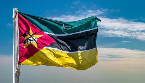 The flag of Mozambique, fluttering in the wind, isolated, against the blue sky