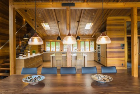 Illuminated industrial style copper with frosted glass pendant lighting fixtures over wooden dining