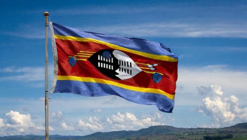 The flag of Swaziland, Kingdom of Eswatini, flutters in the wind, isolated, against the blue sky