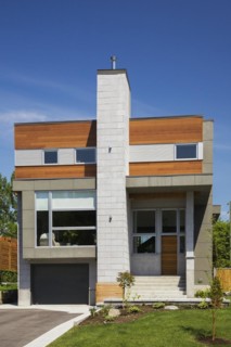 Two story grey and charcoal stone with cedar wood siding modern cube style home facade in summer,