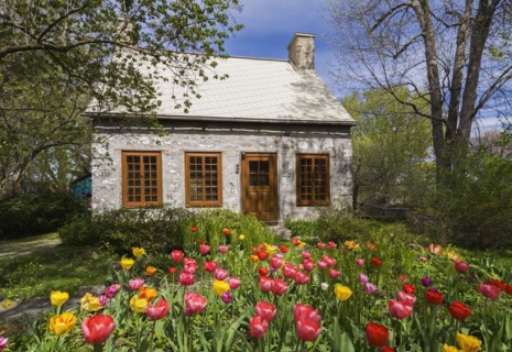 Old circa 1750 Canadiana style fieldstone house facade with brown stained wooden windows, door and