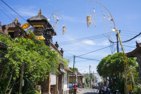 Ornate jewellery woven from palm leaves on bamboo poles, on a village street in Amed, Karangasem,