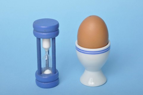 Boiled egg and hourglass on a blue background