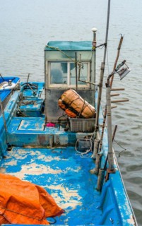 A close-up of a boat's cabin with fishing gear, highlighting the wear and decay, in South Korea