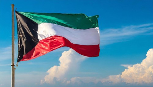 The flag of Kuwait flutters in the wind, isolated against a blue sky